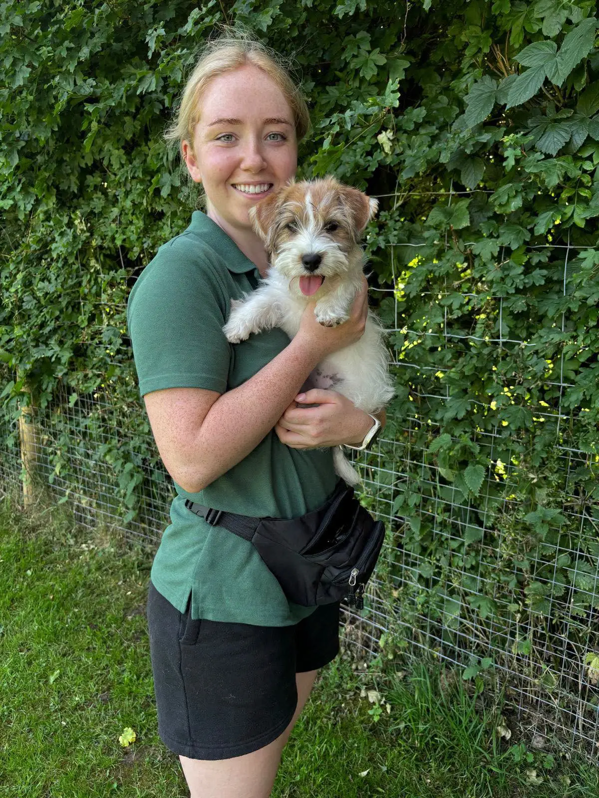 A member of the Leafields team holding a happy small dog in the grounds